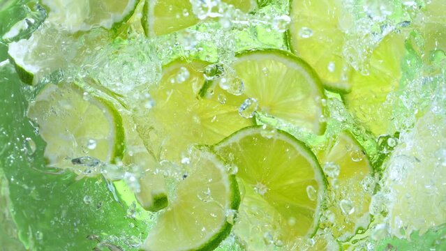 Super Slow Motion Shot of Fresh Lime Slices Falling into Water Whirl at 1000 fps.