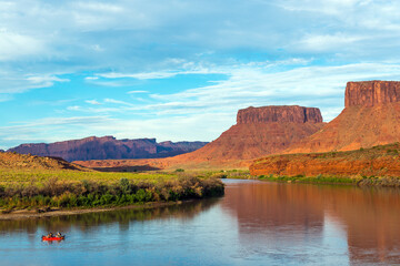 People rafting on Colorado river with table mountains at sunset near Moab, Arches national park,...