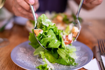 Traditional Caesar salad with green lettuce, parmesan cheese, chicken, croutons and dressing served on a blue plate