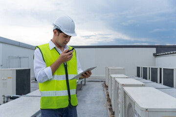 Asian maintenance engineer works on the roof of factory. contractor inspect compressor system and plans installation of air condition systems in construction. technology, online, mobile application.