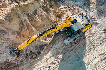 Aerial view of excavator working in quarry or construction site. Industrial top view background...