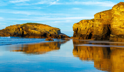 Beautiful beach and rock formation with reflection in atlantic ocean at sunset- galicia, Spain
