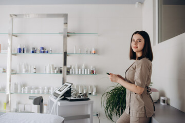 Smiling young female doctor wearing white medical uniform and stethoscope using modern smartphone gadget, positive millennial woman nurse or GP text message on cellphone, consult patient online.