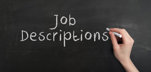 A woman's hand write text Job descriptions with chalk on chalkboard