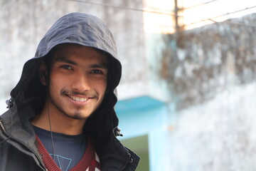 A YOUNG beautiful handsome BOY SMILING IN portrait. wearing hoodie, outside in street looking in camera.
