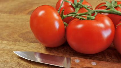  grappe de tomates rouges, en gros plan, sur une planche à découper