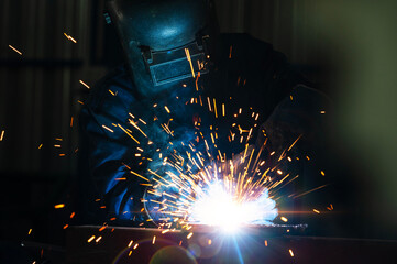 Industrial workers at steel structure welding plant A welder is welding metal parts in a small workshop.