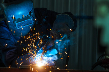 Industrial workers at steel structure welding plant A welder is welding metal parts in a small workshop.
