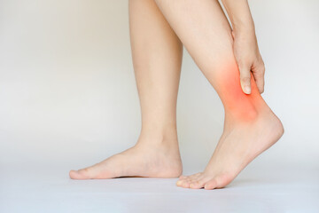 A woman grabs her ankle because she sprained her ankle from incorrect exercise.