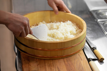 Chef cooking japanese sushi rice in the wooden bowl