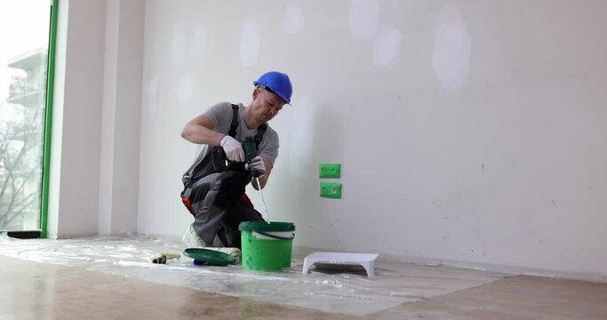 Builder painter stirs building mixture in bucket. Construction worker mixes paint in construction bucket