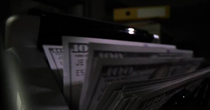 Closeup of bank machine for counting cash on dark background. One hundred dollar bills currency exchange and machine counts money
