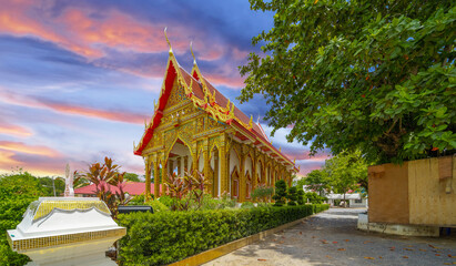 Beautiful Wat Buddhist temple in Phuket Karon Thailand. Decorated in beautiful ornate colours of Gold blue green red and White. Sunset Sunrise lovely sky and cloud colours