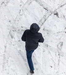 Fototapeta na wymiar A man walks on white snow in winter. View from above