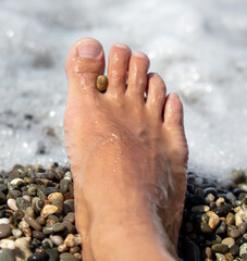 Man's foot on a pebble beach