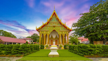 Beautiful Wat Buddhist temple in Phuket Karon Thailand. Decorated in beautiful ornate colours of Gold blue green red and White. Sunset Sunrise lovely sky and cloud colours