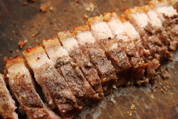 Pieces of sliced asian roasted pork belly on top of a wood surface