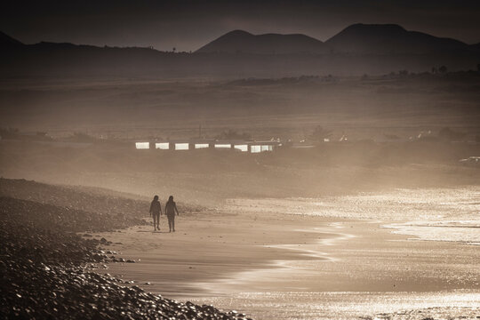 surfers coming out of the water at sunset