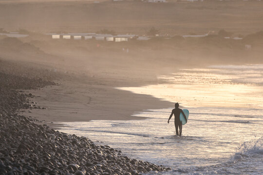 surfer coming out of the water at sunset