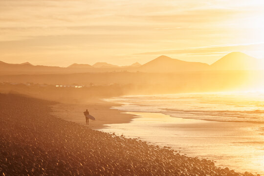 surfer coming out of the water at sunset