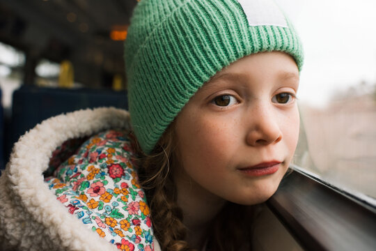 Portrait of a young girl sat on a train looking out the window
