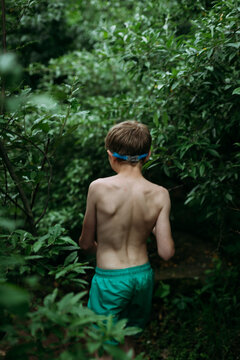 Shirtless boy hiking through jungle in summer