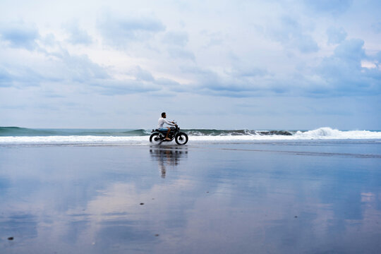 Man travels on a motorcycle in the ocean beach.
