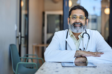 Portrait of smiling male healthcare worker sitting at desk in clinic