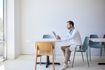 Side view of male doctor using tablet PC while sitting on chair