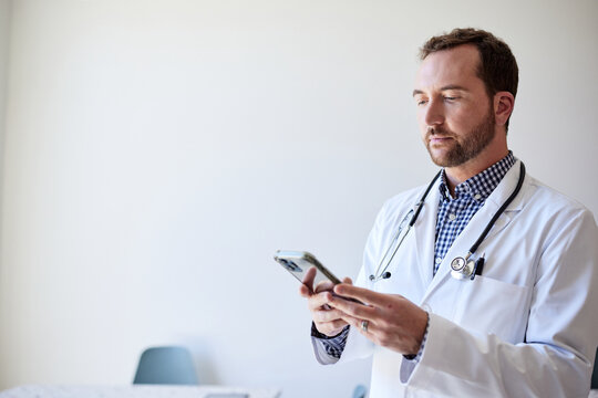 Male healthcare worker using smart phone while standing in clinic