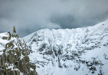 Male mountaineer stands on edge of cliff in winter, Katahdin, Maine