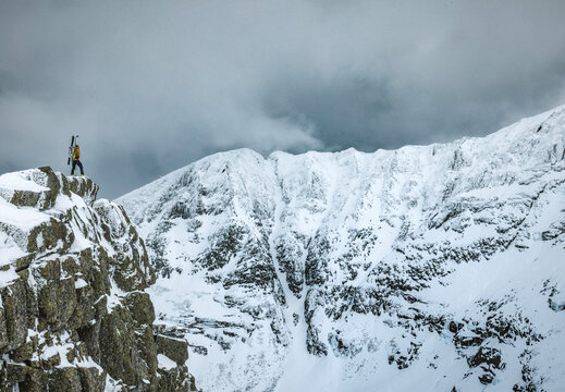 Male mountaineer stands on edge of cliff in winter, Katahdin, Maine
