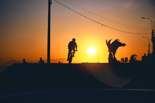 Urban athlete biker performing acrobatic jump at public park