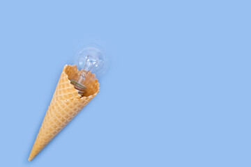 Waffle ice cream cone with a hidden glass extinguished round light bulb on a blue background