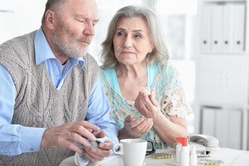 ill senior woman with pills while husband sitting nearby
