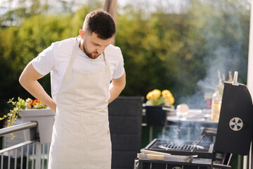 Man puts on an apron outdoor. Preparing for BBQ grill