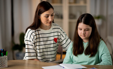 Mother is helping daughter with homework after school. Mom checking daughter's notebook
