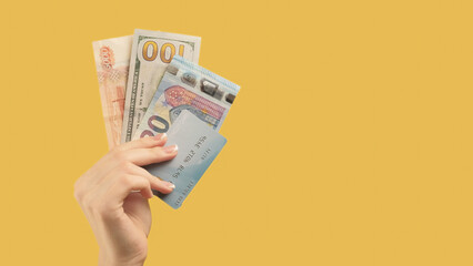 International transaction. Financial success. Woman with different types money credit card in hand on yellow background.