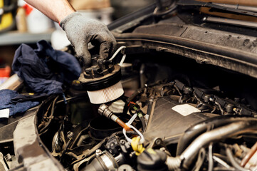 close-up of the hands of a car mechanic changing a new fuel filter. filter replacement in the car. car repair service. clean fuel filter