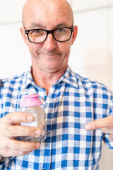 A man demonstrates a tube with a valve and a hinged connection for intravenous fluid injections to an implanted port for chemotherapy