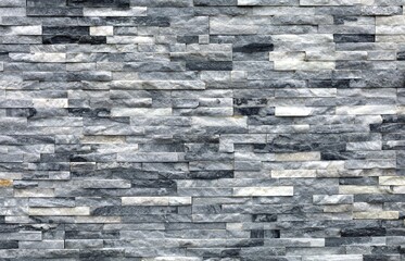 Stone cladding wall made of strips of white, gray and black rocks. Panels for exterior. Background...