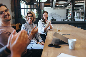 Colleagues applauding during a team meeting in an office - obrazy, fototapety, plakaty