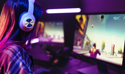Girl playing a first person shooter video game on a computer