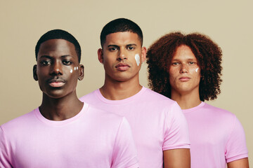 Group of diverse youthful men using a beauty product on their unique skin tones