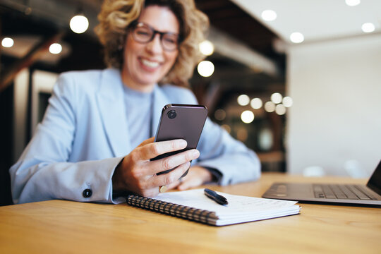 Business woman reading a text message on a mobile phone. Woman working in a coworking office - Powered by Adobe