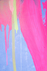 Messy paint strokes and smudges on an old painted wall. Purple, blue, pink, magenta, yellow drips, flows, streaks of paint and paint sprays