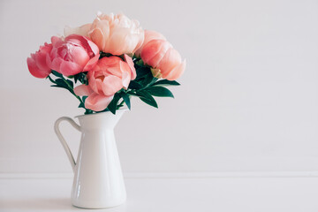 Beautiful bouquet of fresh coral peony flowers in full bloom in vase. Floral still life with blooming peonies. Negative space for text.