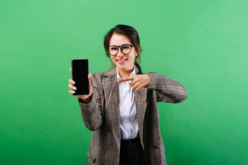 Photo of smiling Asian businesswoman showing mobile phone screen with hands pointing on blank phone screen on isolated green background