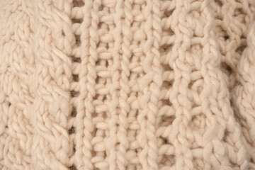 A fragment of beige knitted fabric, knitted from white sheep wool.