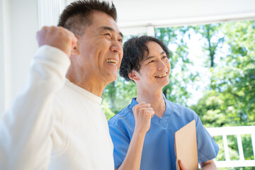 ガッツポーズをする介護士と日本人シニア男性